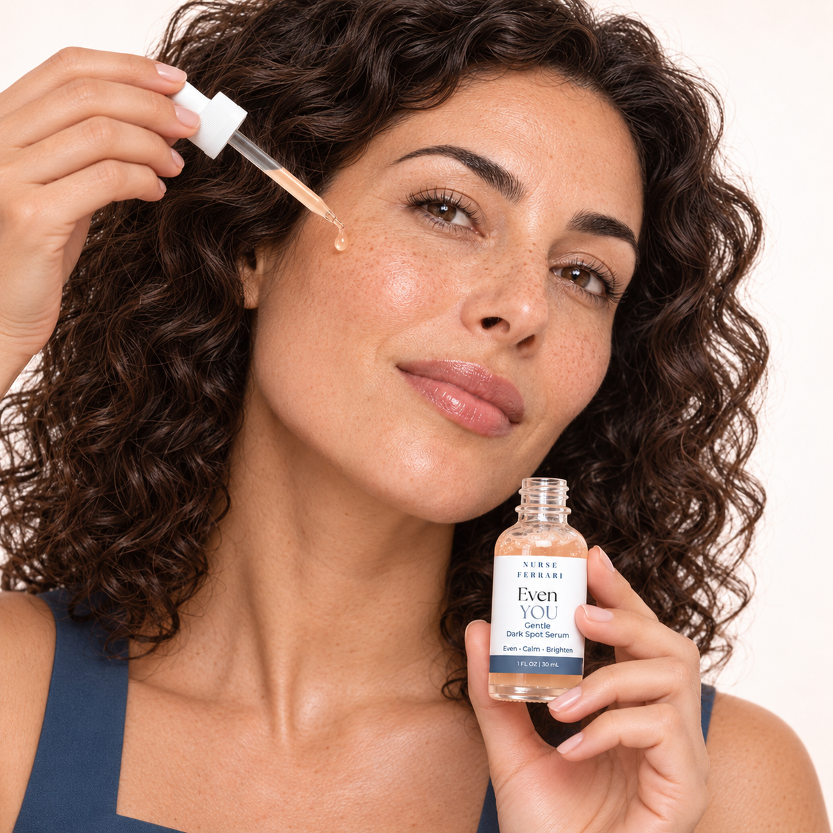 Curly-haired woman applying the true pale-peach Even YOU serum with the correct white dropper